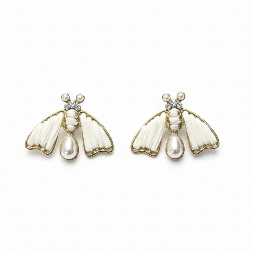 Pair of bee-shaped earrings with pearl accents on a wooden surface