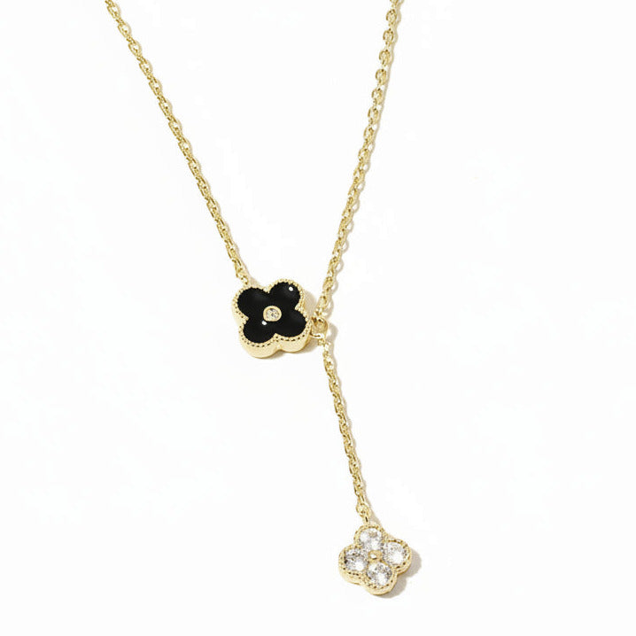 Gold necklace with black and white floral pendants on a white background