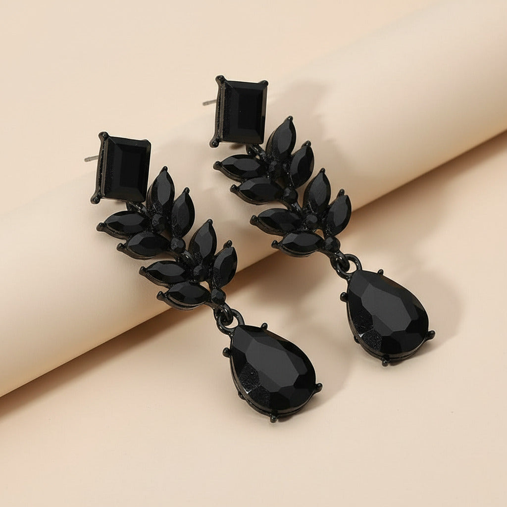 Black earrings with multiple gemstones on a neutral background