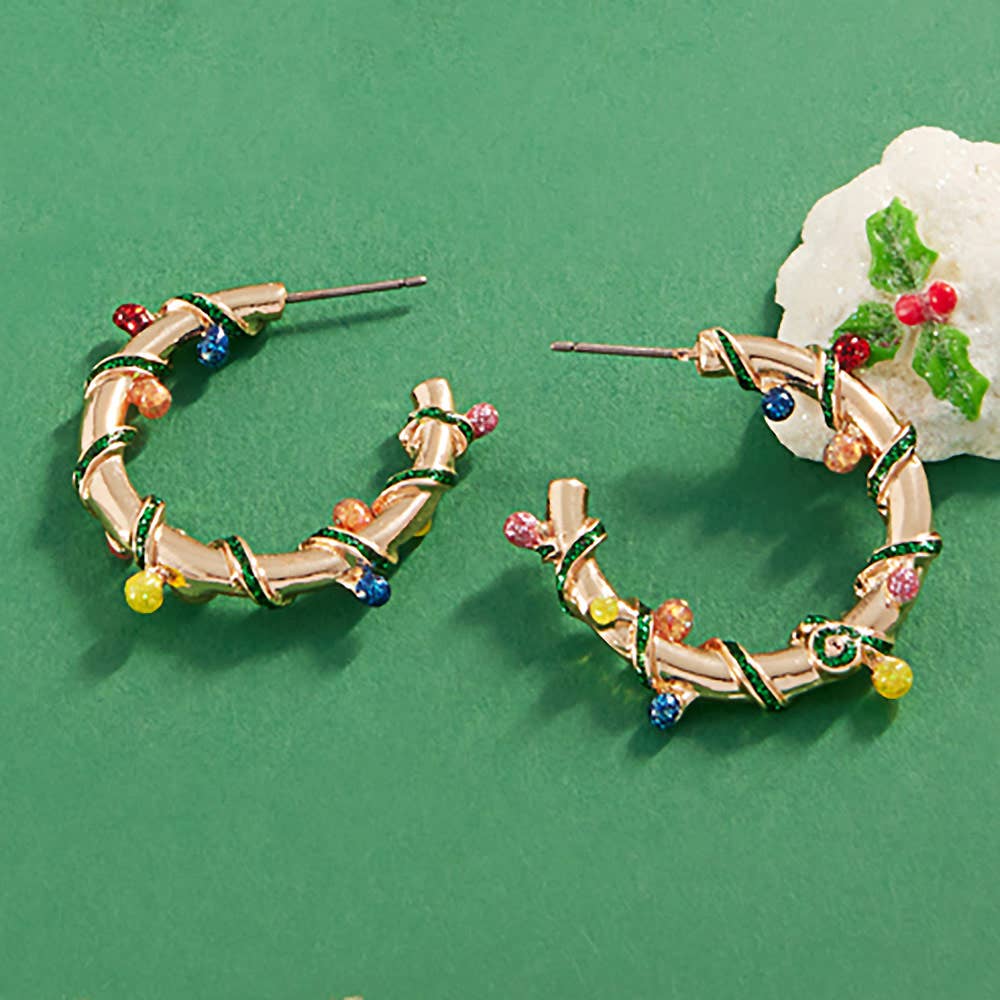 Gold hoop earrings with christmas lights on a green background