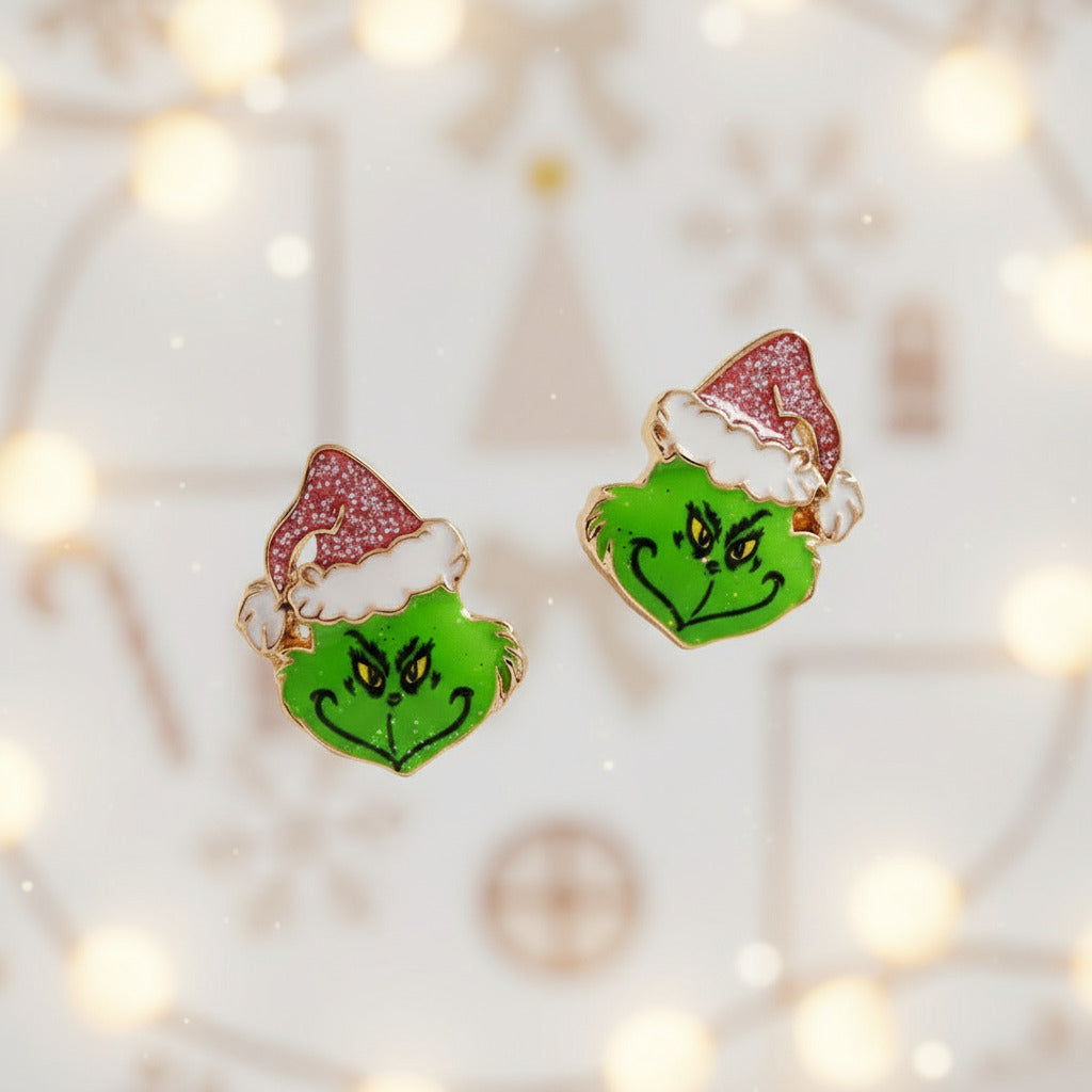 Pair of earrings shaped like the Grinch with a pink hat on a light background