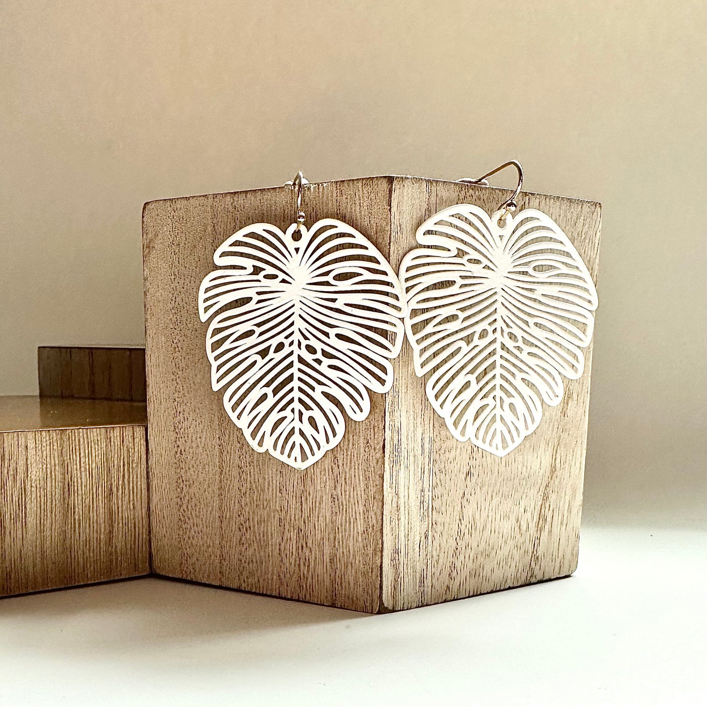 matte white palm tree earrings against a wood block
