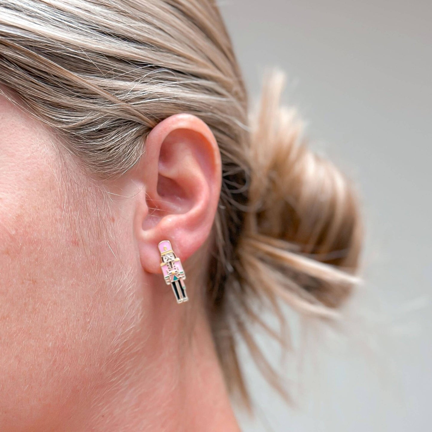 pink nutcracker earrings shown in a womans ear