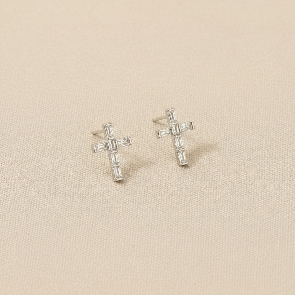 Cross-shaped earrings on rhodium and gold-dipped cards with visible brand logo.