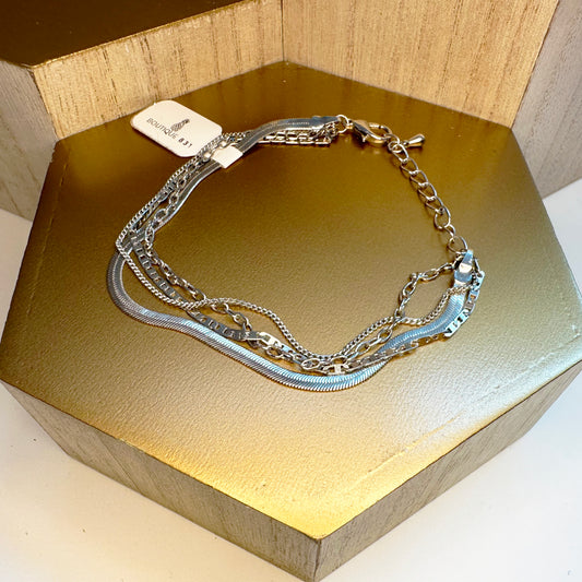 A silver multistrand bracelet with a lobster claw clasp, displayed on a gold-colored surface.