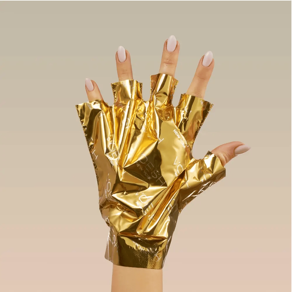 Gold foil gloves being worn on a neutral background