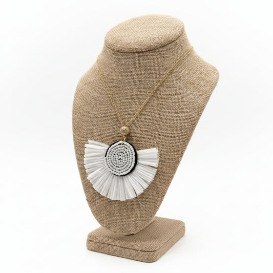 Necklace with a large circular pendant on a beige jewelry stand against a white background