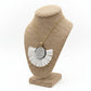 Necklace with a large circular pendant on a beige jewelry stand against a white background