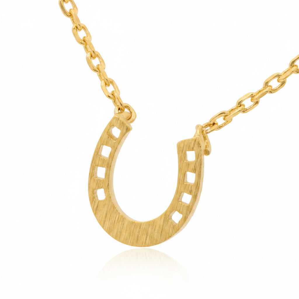 Gold horseshoe necklace on a white background