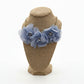 Blue floral necklace on a brown mannequin bust with white background
