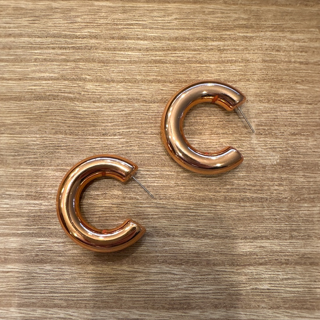 Pair of copper hoop earrings on a wooden surface