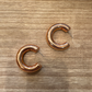 Pair of copper hoop earrings on a wooden surface