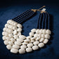 Necklace with white and navy beads on a blue surface