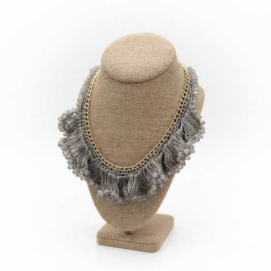 Necklace with fringe and beads on a mannequin bust.