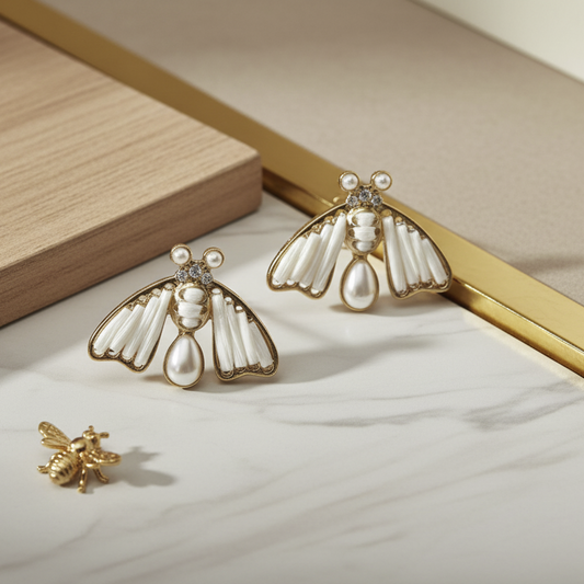 Pair of bee-shaped earrings with pearl accents on a white background