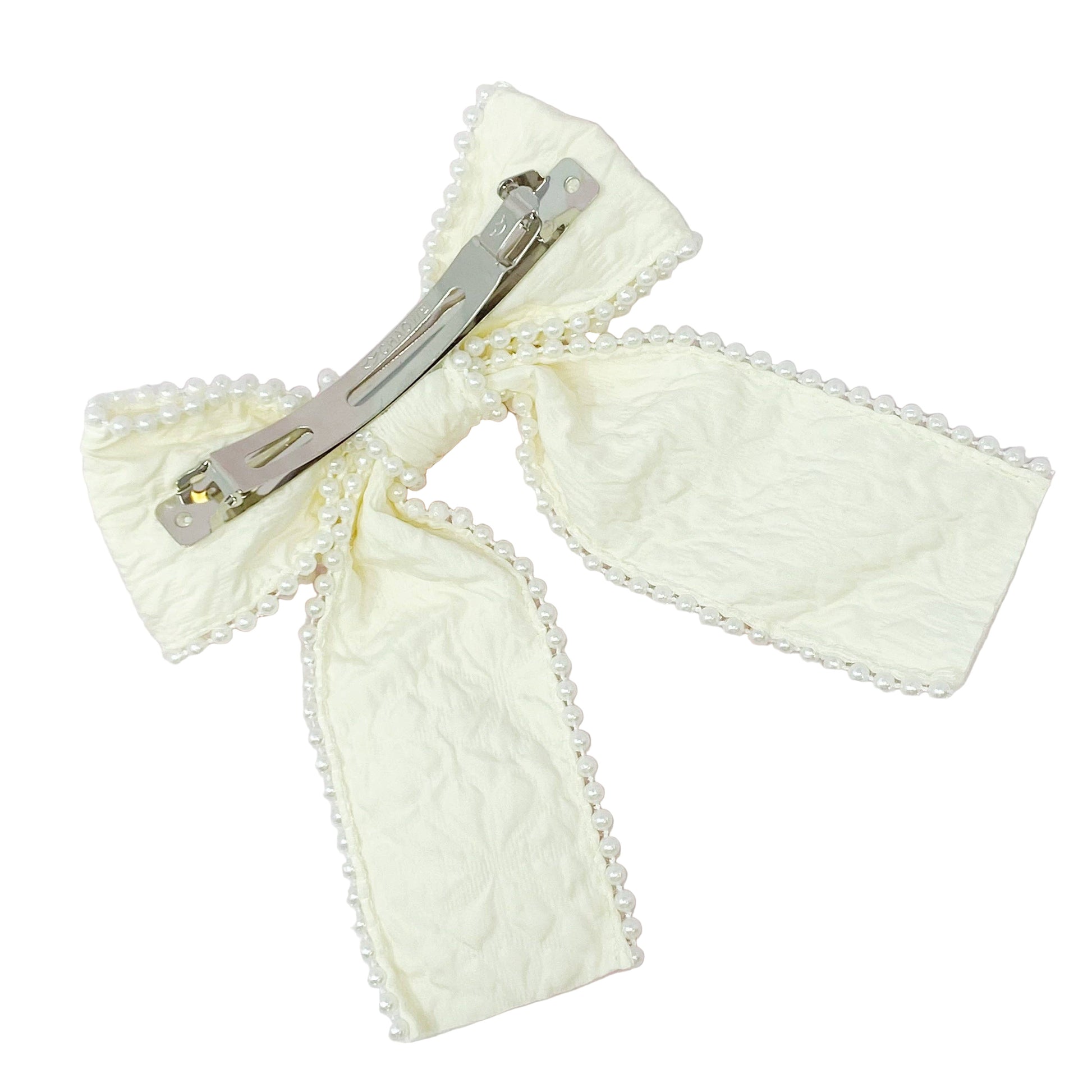 Cream-colored bow hair clip on a white marble background