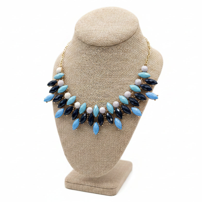 Necklace with blue, navy, and white beads on a brown bust