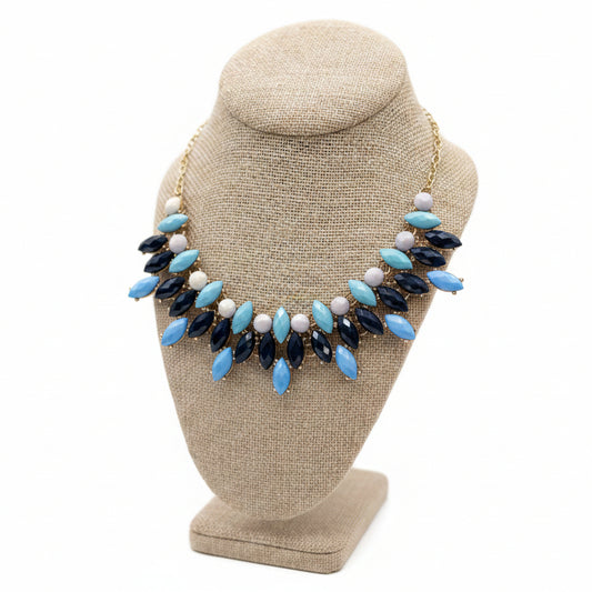 Necklace with blue, navy, and white beads on a brown bust