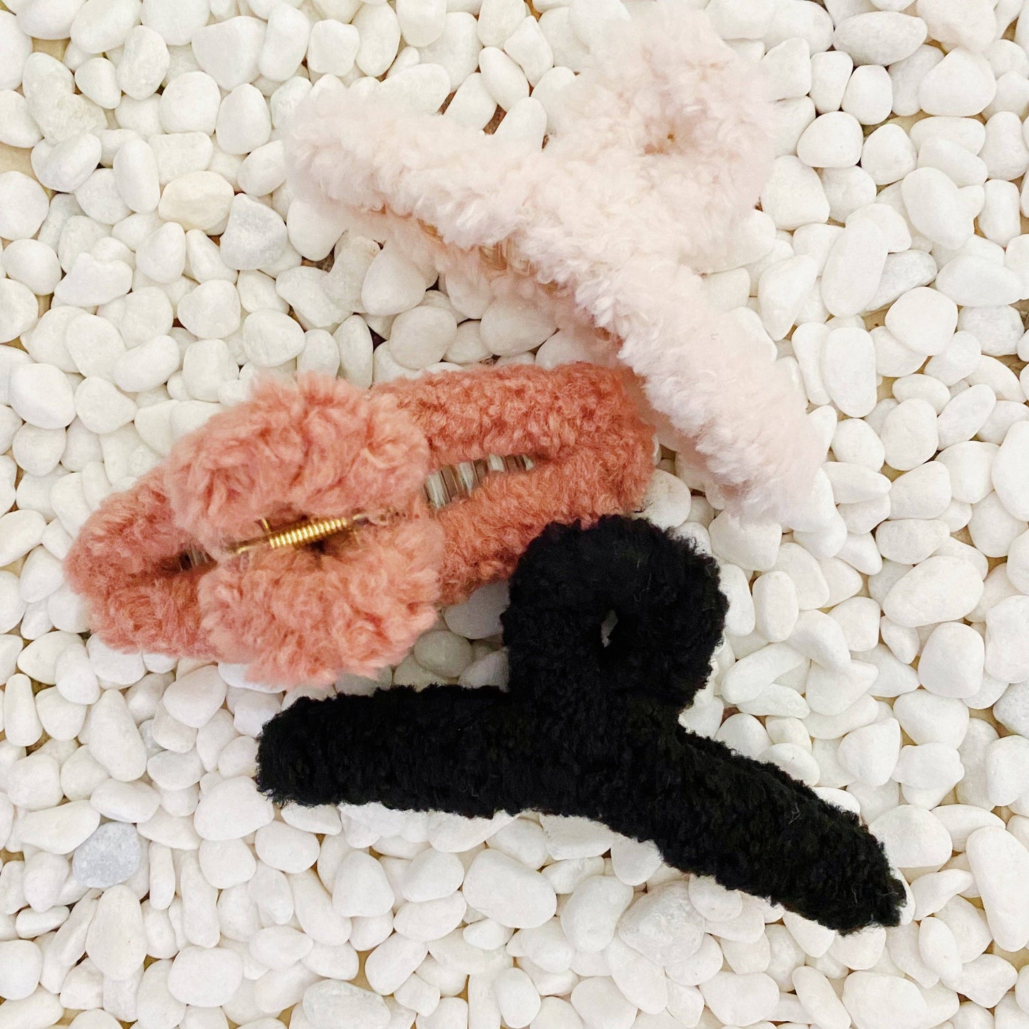 Fluffy white, tan and black hair clips  on pebbles