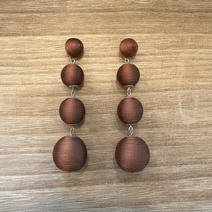 Pair of brown drop earrings on a wooden surface