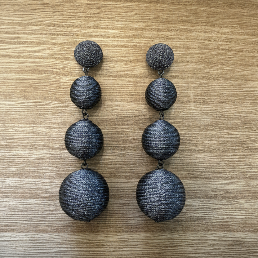 Pair of silver threaded earrings on a wooden surface.