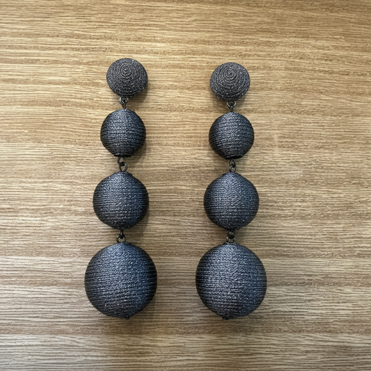 Pair of silver threaded earrings on a wooden surface.