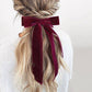 Blonde hair styled in a bun with a burgundy ribbon against a light background
