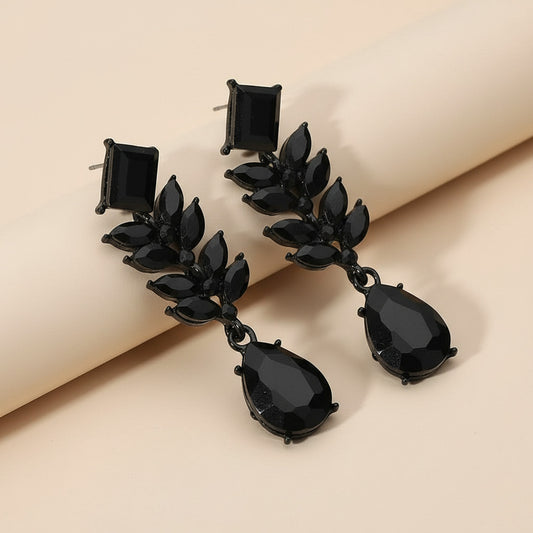 Black earrings with multiple gemstones on a neutral background