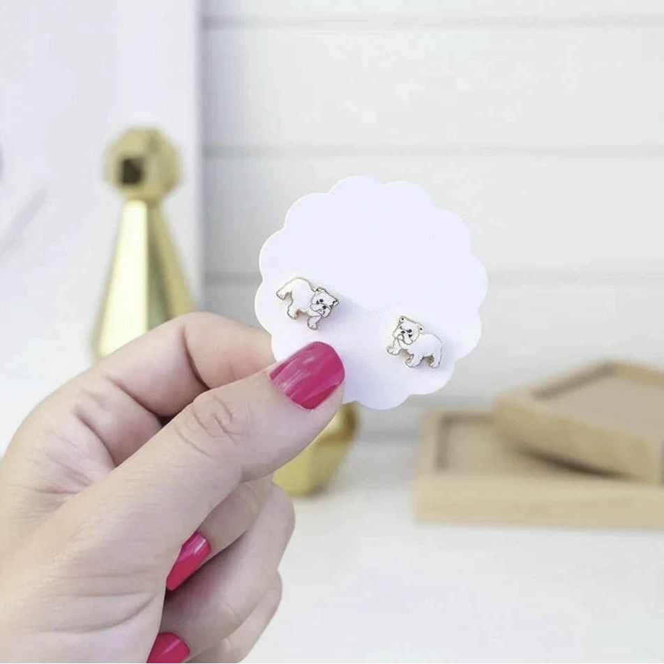 Hand holding a card with earrings against a grassy background