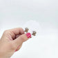 Hand holding a pair of dog earrings against a white background