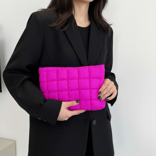 Person holding a pink quilted clutch bag against a white background