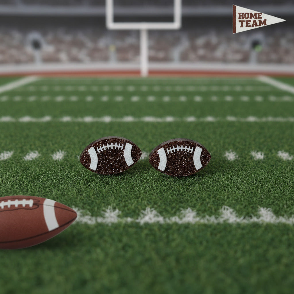 Football earrings on a football field with a blurred stadium background