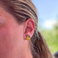 a pair of lemon stud earrings shown in a females ear