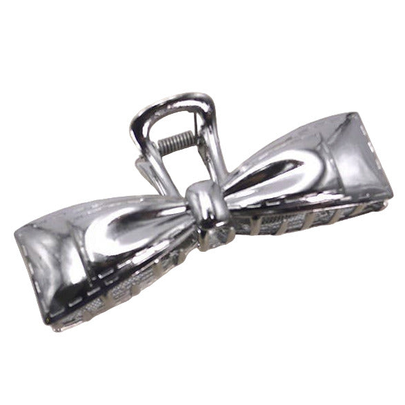 Silver bow-shaped hair clip on a beige background