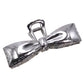 Silver bow-shaped hair clip on a beige background