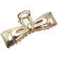 Gold bow-shaped hair clip on a white background