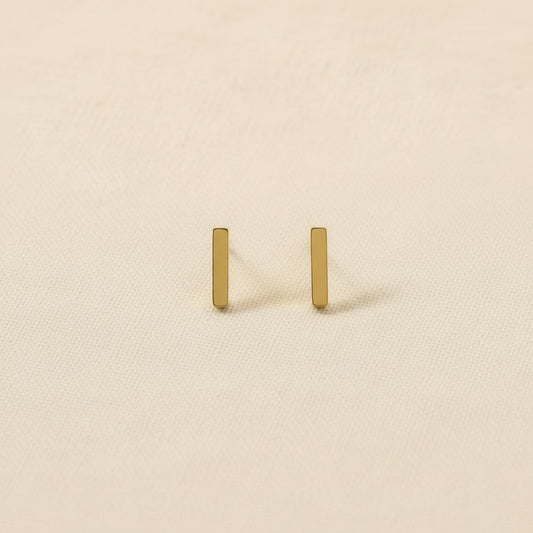 Pair of gold and rhodium plated earrings on neutral background