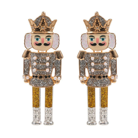 Pair of nutcracker-shaped earrings with glittery details on a white background