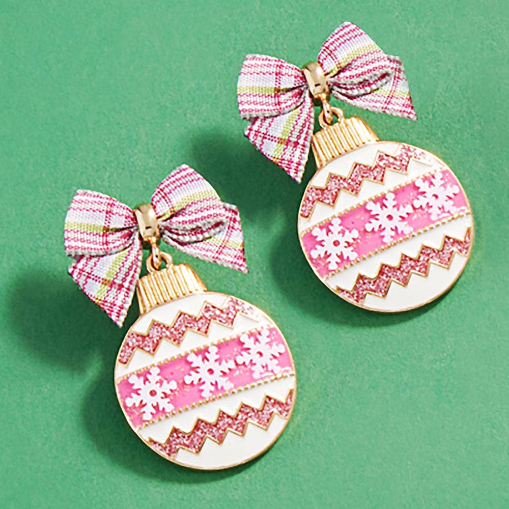 Two decorative earrings with pink and white patterns and plaid bows on a green background