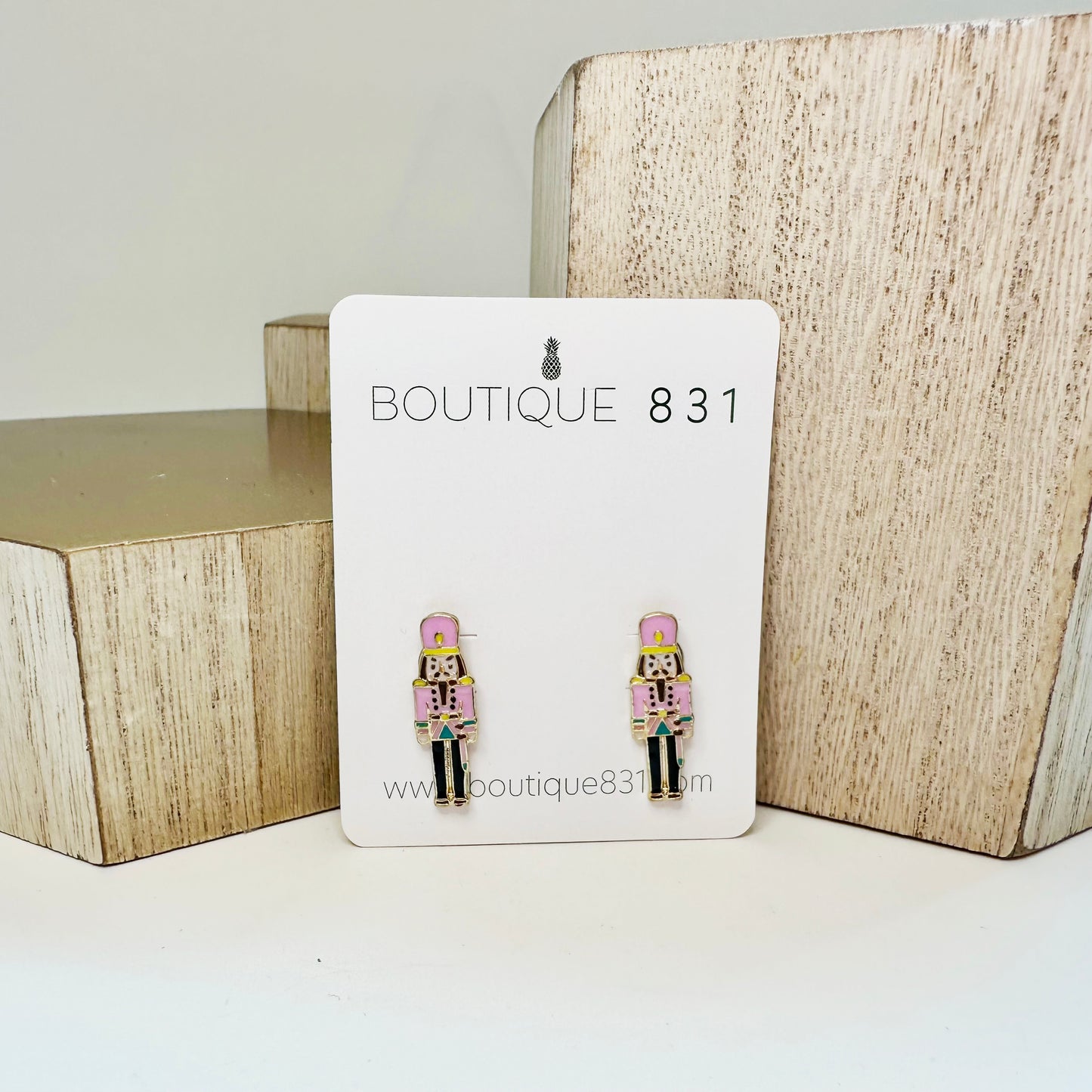 Stud earrings with pink nutcracker enamel design displayed on a card with 'Boutique 831' branding.