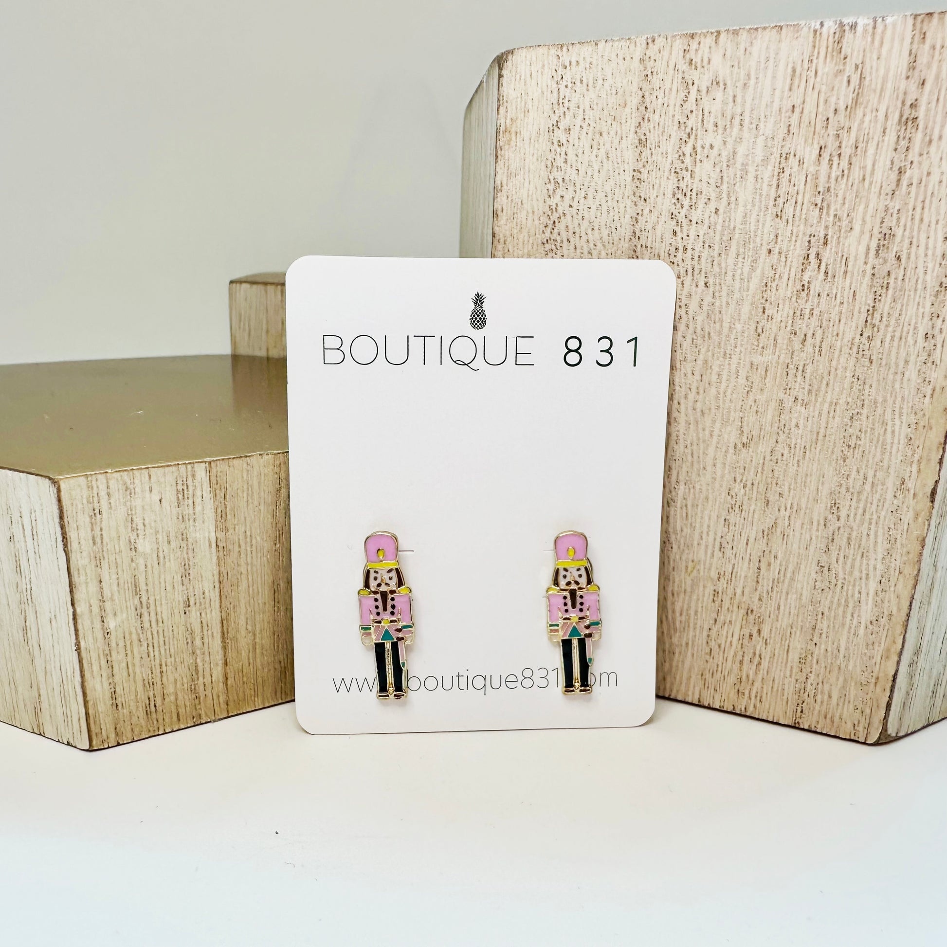 Stud earrings with pink nutcracker enamel design displayed on a card with 'Boutique 831' branding.