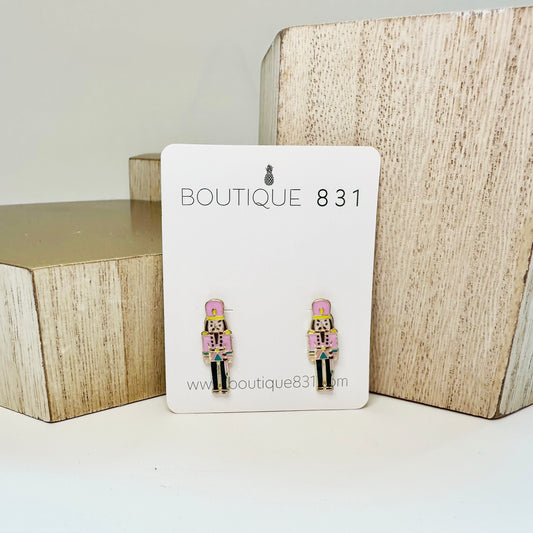 Stud earrings with pink nutcracker enamel design displayed on a card with 'Boutique 831' branding.
