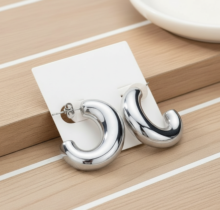 Silver hoop earrings on a white card against a wooden background