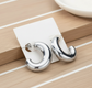 Silver hoop earrings on a white card against a wooden background