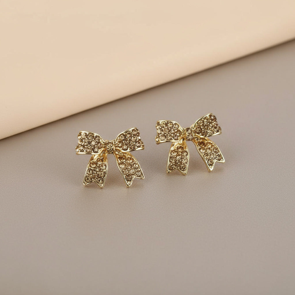 Gold bow-shaped earrings on a 'neutral background