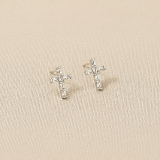 Cross-shaped earrings on rhodium and gold-dipped cards with visible brand logo.
