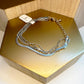 A silver multistrand bracelet with a lobster claw clasp, displayed on a gold-colored surface.