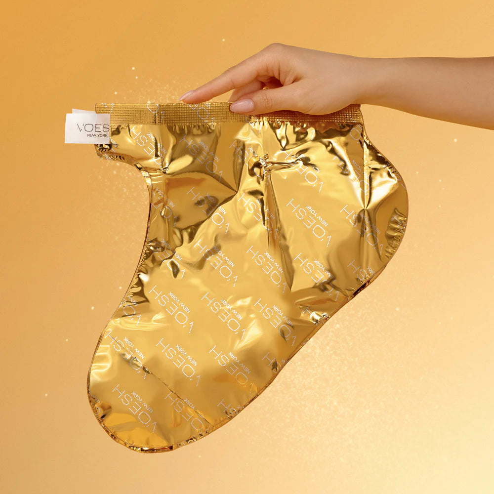 Gold foil sock held by a hand on a beige background