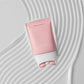Pink skincare product on a textured white background