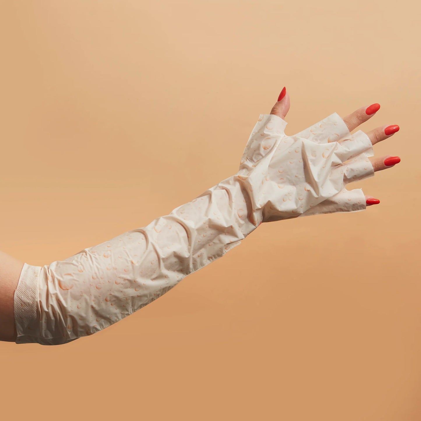 White disposable gloves worn by a person with red nail polish on a beige background